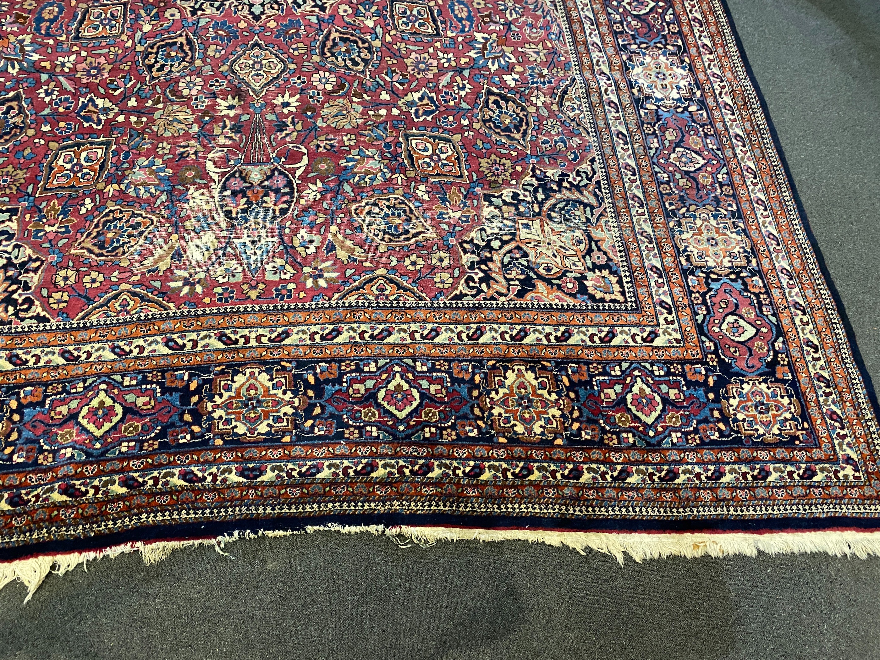 An early 20th century Heriz burgundy ground carpet, 412 x 305cm